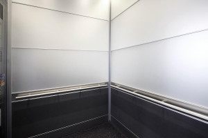 FSRT750 Интерьер лифта Levele-104 с захватными панелями из стекла vivichrome chromis с белой прослойкой и отделкой opalex, клееный алюминий с темной патиной и рисунком ustin, нержавеющая сталь с отделкой seastone; круглые поручни в павильоне амбулаторной Forms-surfaces 